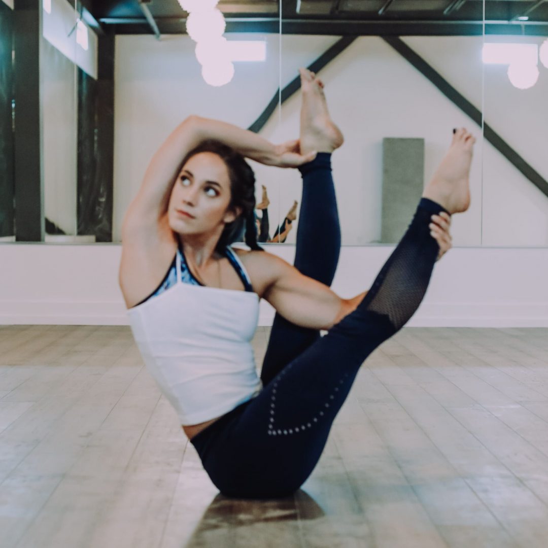 Woman in a Yoga Post in from of a mirror in a gym room